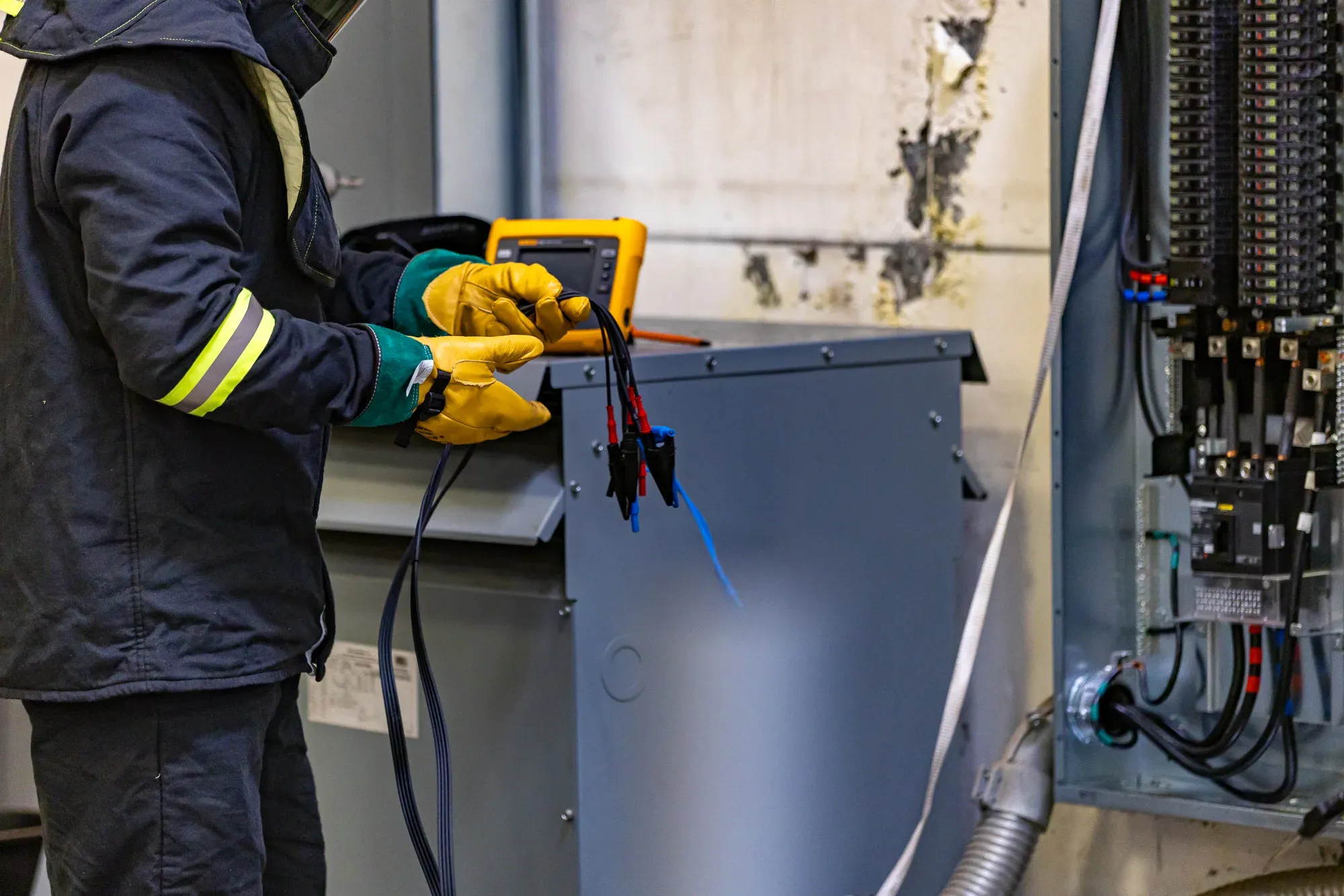 Electrician using multimeter to test electrical transformer during troubleshooting