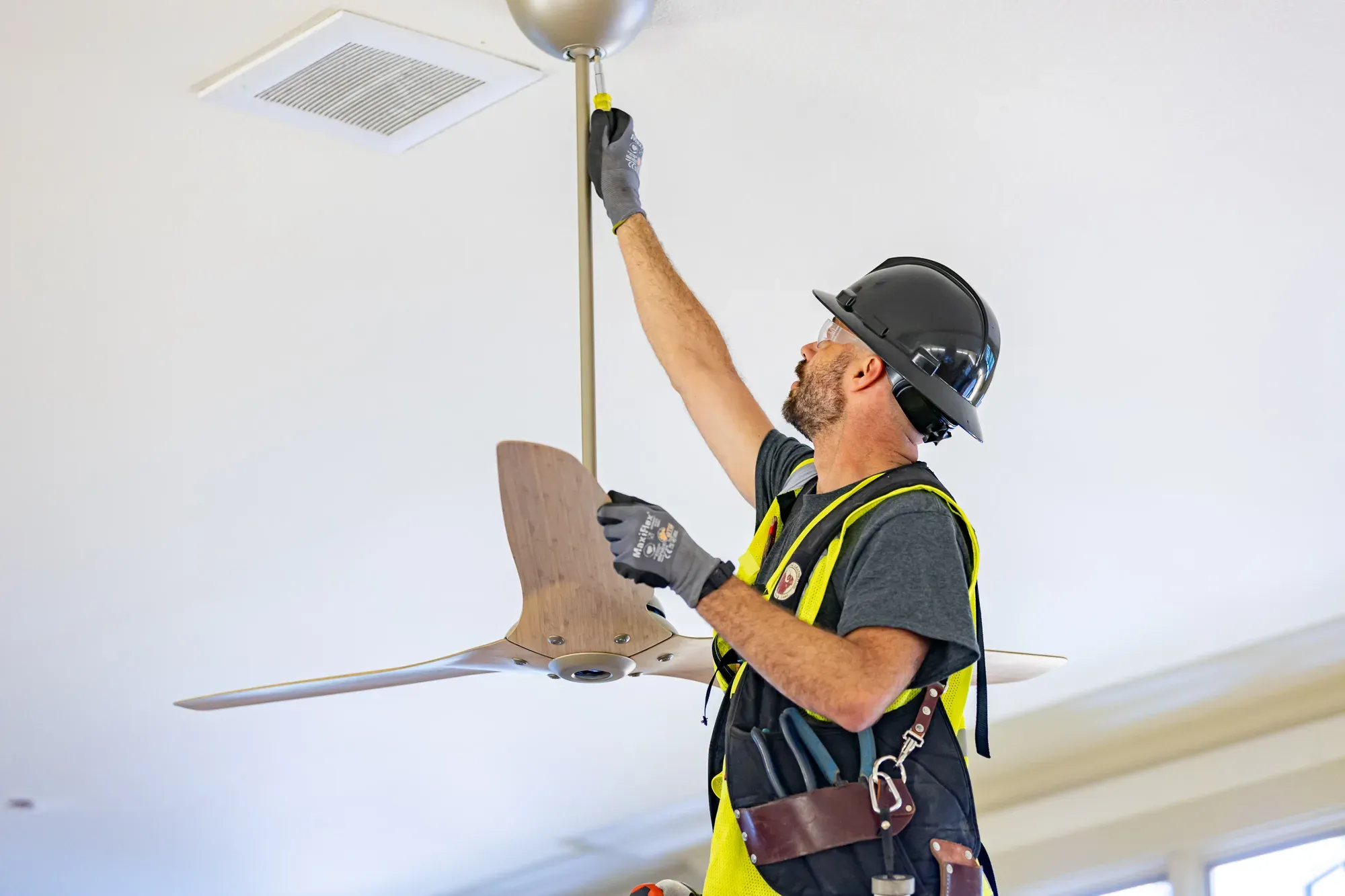 Licensed electrician installing a ceiling fan in a residential home