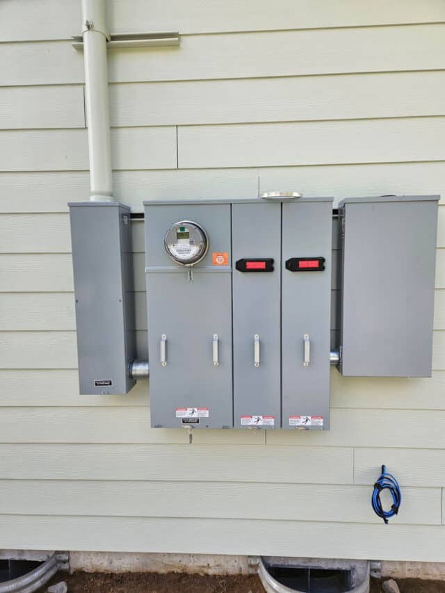 Electric meter and utility boxes on exterior wall.